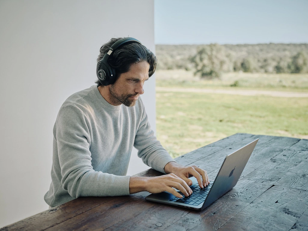 Focal bathys black hodetelefoner. Mann hører på hodetelefoner mens han jobber på laptop. Head-fi